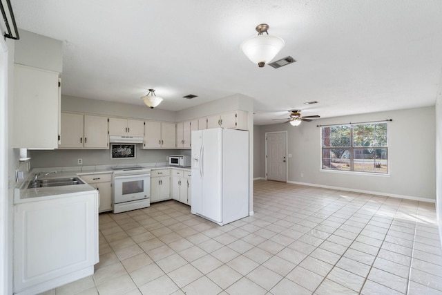 kitchen with sink, white appliances, light tile patterned floors, ceiling fan, and white cabinets