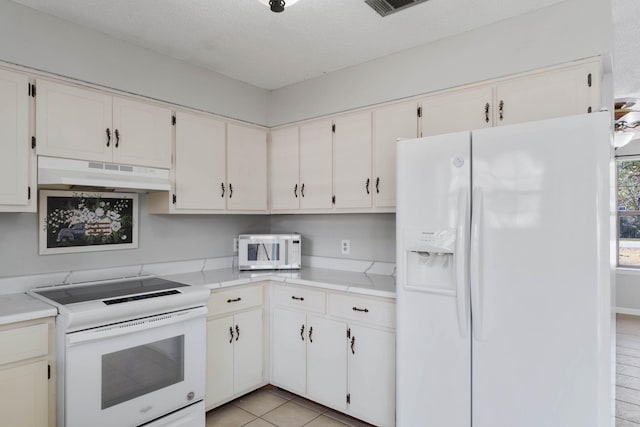 kitchen featuring white cabinetry, white appliances, a textured ceiling, and light tile patterned floors