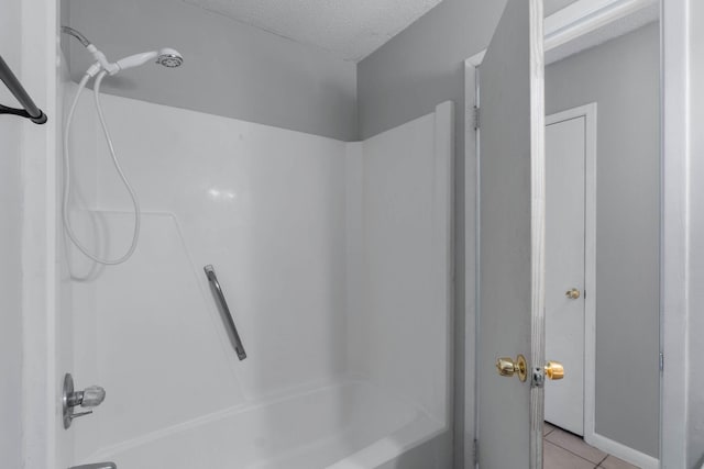 bathroom featuring tile patterned flooring, shower / washtub combination, and a textured ceiling