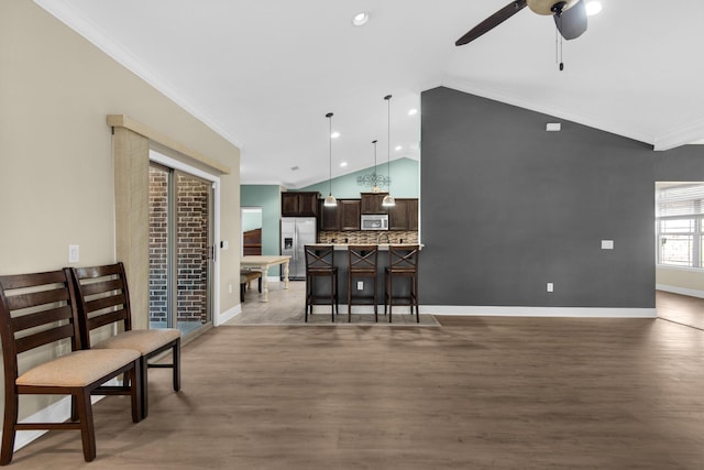 living room with lofted ceiling, dark wood-type flooring, ceiling fan, and crown molding