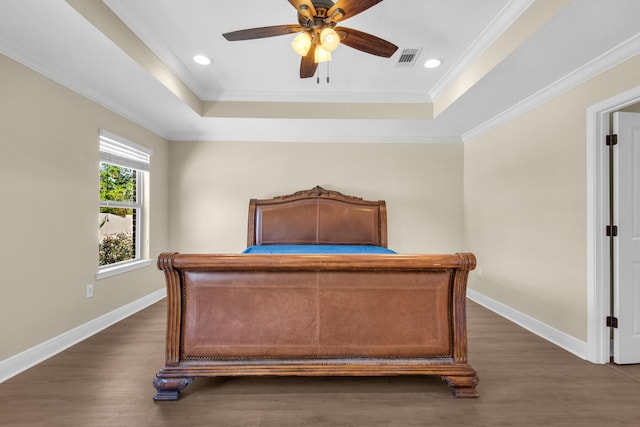 bedroom with ornamental molding, ceiling fan, a tray ceiling, and dark hardwood / wood-style floors