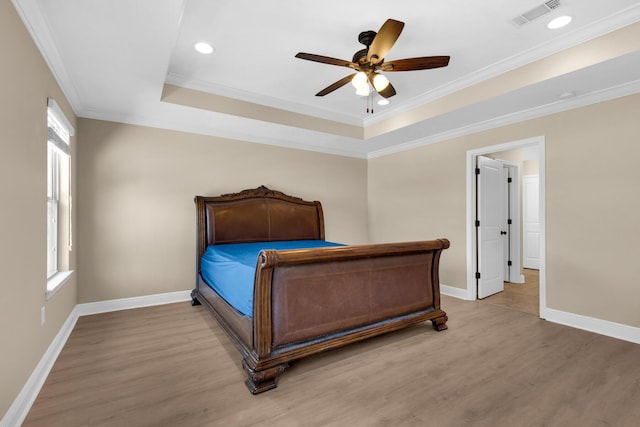 bedroom featuring ceiling fan, crown molding, light hardwood / wood-style floors, and a raised ceiling