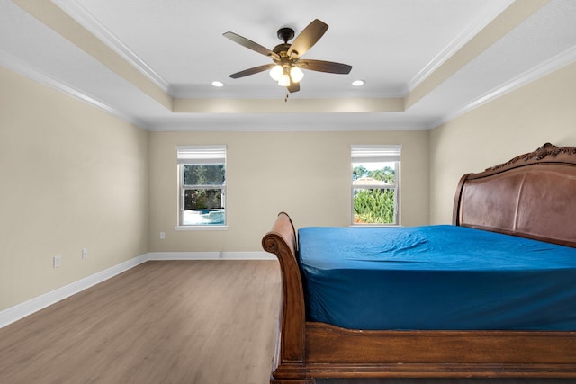 bedroom with a raised ceiling, ceiling fan, light hardwood / wood-style floors, and crown molding