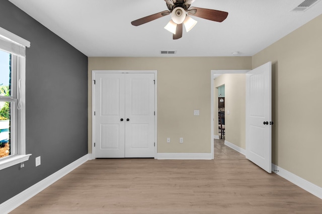 unfurnished bedroom featuring ceiling fan, light hardwood / wood-style floors, and a closet