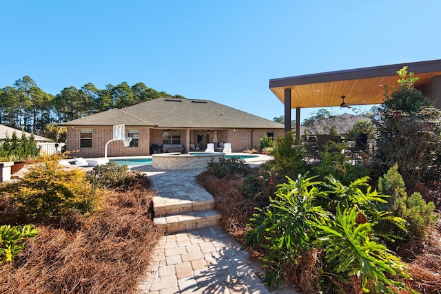 back of property with a patio area, ceiling fan, and a swimming pool with hot tub