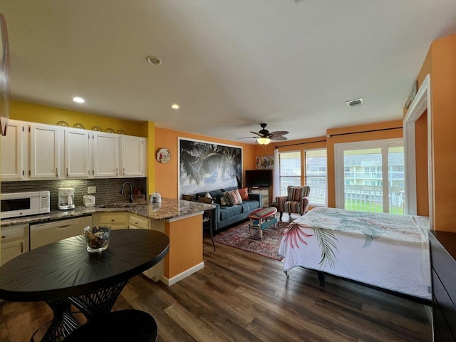 kitchen featuring white appliances, kitchen peninsula, dark stone countertops, decorative backsplash, and ceiling fan