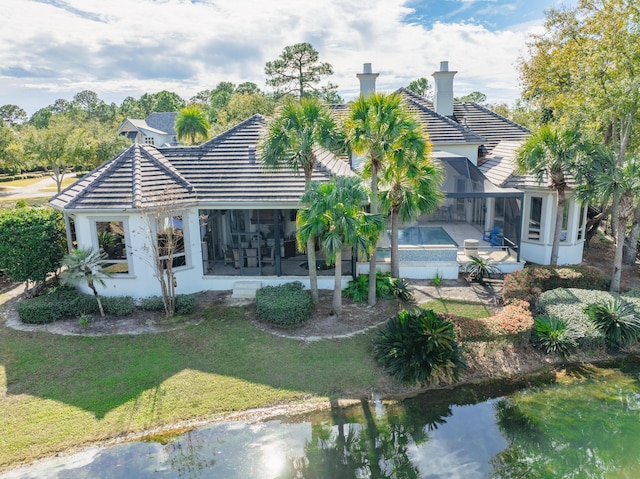 back of property with a sunroom, a water view, a patio, a lanai, and a lawn