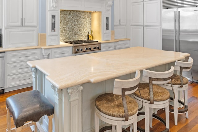 kitchen featuring white cabinetry, appliances with stainless steel finishes, backsplash, and a breakfast bar