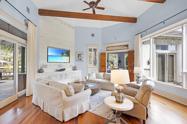 living room featuring ceiling fan, plenty of natural light, beamed ceiling, and hardwood / wood-style floors