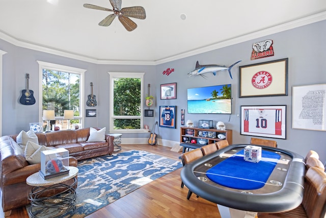 rec room with ceiling fan, wood-type flooring, and ornamental molding