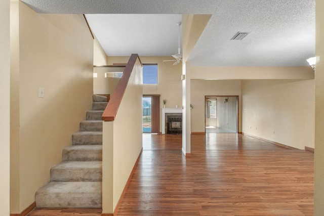 unfurnished living room with ceiling fan, a textured ceiling, and hardwood / wood-style flooring