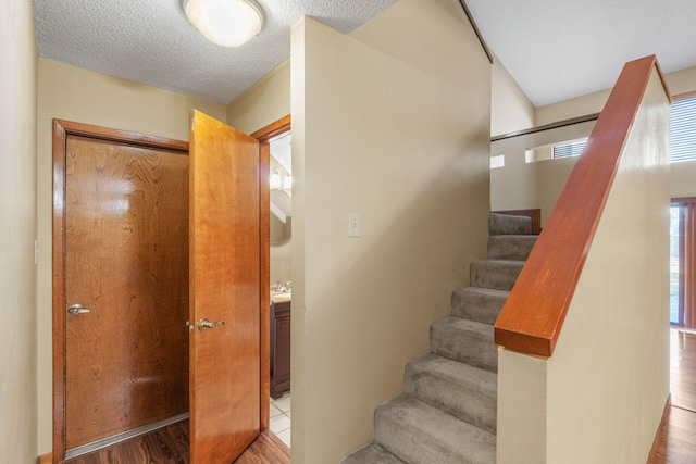 stairs with wood-type flooring and a textured ceiling