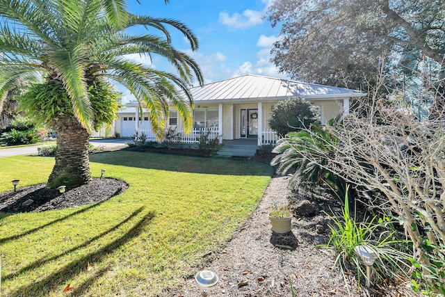 view of front of property with a garage, metal roof, a standing seam roof, a porch, and a front yard