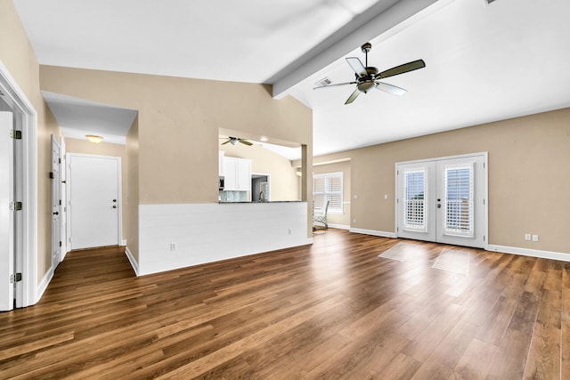 unfurnished living room featuring lofted ceiling with beams, ceiling fan, baseboards, and wood finished floors