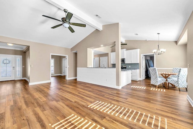 unfurnished living room featuring light wood finished floors, baseboards, visible vents, lofted ceiling with beams, and ceiling fan with notable chandelier