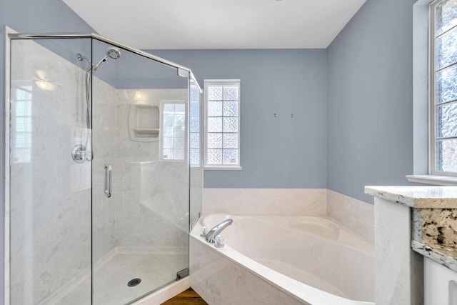 bathroom featuring a garden tub, a shower stall, and a wealth of natural light