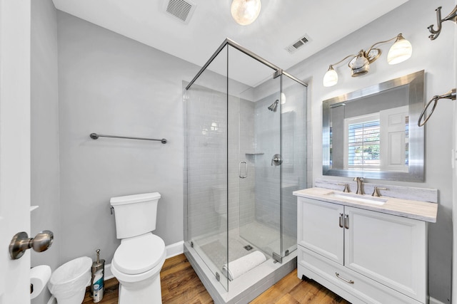 bathroom with a stall shower, wood finished floors, and visible vents