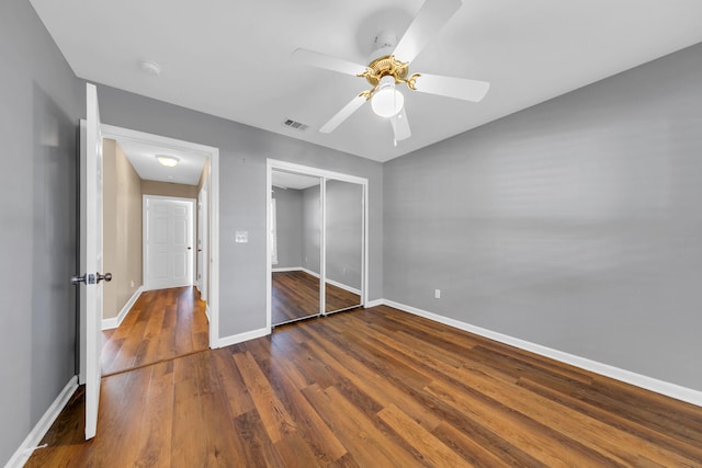 unfurnished bedroom featuring dark wood finished floors, a closet, visible vents, a ceiling fan, and baseboards