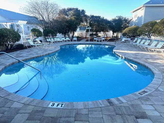 community pool with a patio and fence