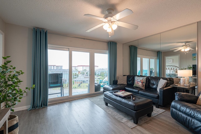 living room with hardwood / wood-style flooring, ceiling fan, and a textured ceiling