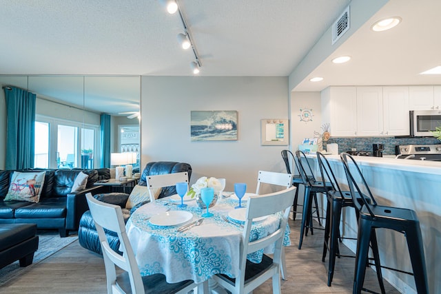 dining area featuring light hardwood / wood-style flooring and a textured ceiling