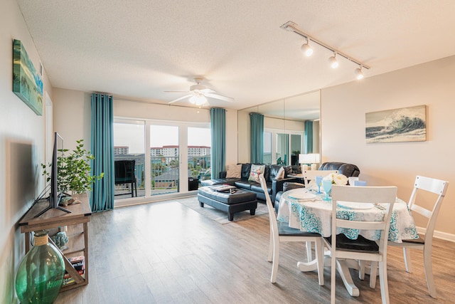 dining space featuring hardwood / wood-style floors, a textured ceiling, rail lighting, and ceiling fan