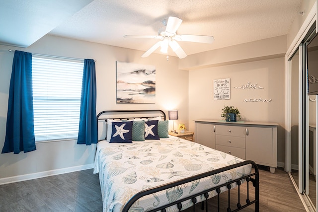 bedroom featuring multiple windows, ceiling fan, a closet, and dark hardwood / wood-style floors