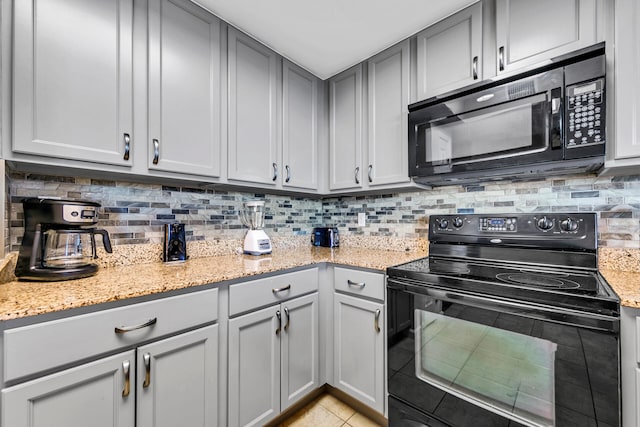 kitchen with light stone countertops, tasteful backsplash, gray cabinets, light tile patterned floors, and black appliances