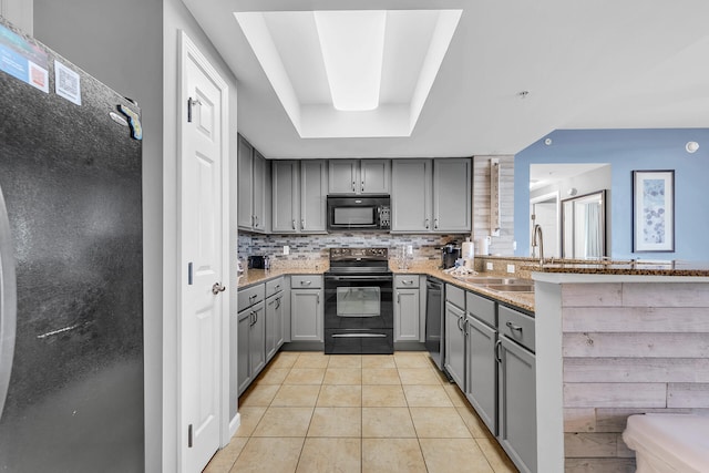 kitchen with black appliances, sink, decorative backsplash, gray cabinets, and light stone countertops