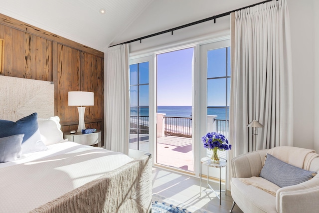 bedroom with lofted ceiling, access to exterior, and a water view