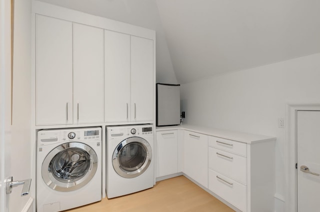 clothes washing area with light wood-type flooring, cabinets, and washing machine and clothes dryer