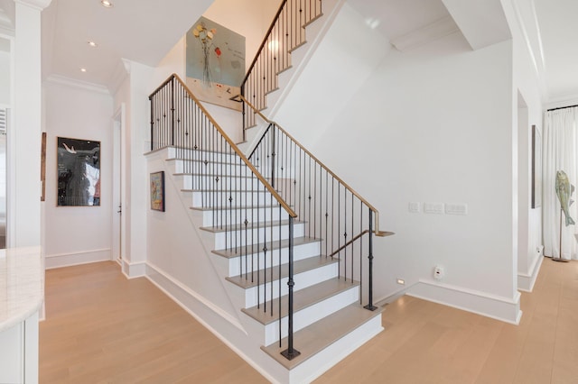 stairs featuring hardwood / wood-style flooring and ornamental molding