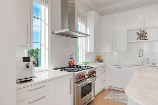 kitchen featuring sink, white cabinetry, wall chimney exhaust hood, plenty of natural light, and designer stove