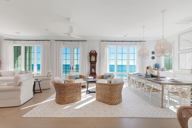 interior space with light hardwood / wood-style floors, a water view, crown molding, and ceiling fan with notable chandelier