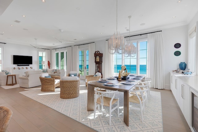 dining area with a water view, plenty of natural light, crown molding, and ceiling fan with notable chandelier