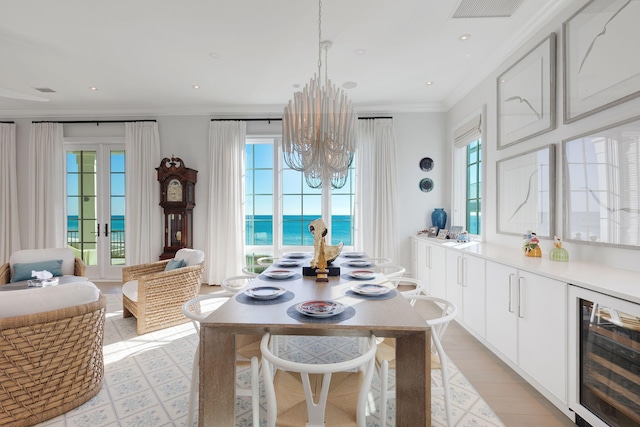 dining area with wine cooler, a water view, crown molding, a notable chandelier, and light hardwood / wood-style flooring