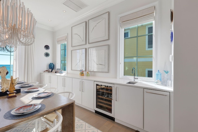 bar with white cabinets, beverage cooler, light wood-type flooring, and a wealth of natural light