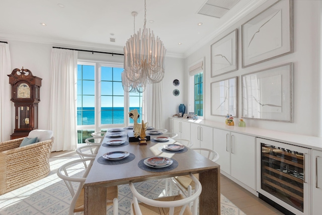 dining space with wine cooler, crown molding, a chandelier, and a water view