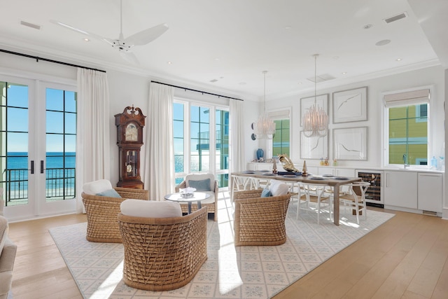 interior space with beverage cooler, light wood-type flooring, crown molding, and a water view