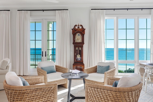 sitting room with french doors, crown molding, a healthy amount of sunlight, and a water view