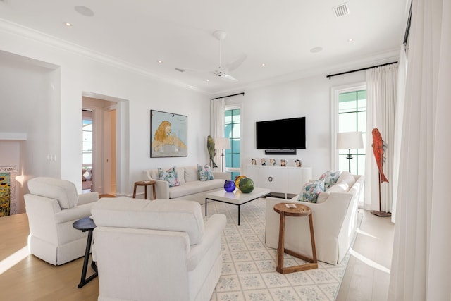 living room with a wealth of natural light, ornamental molding, ceiling fan, and light hardwood / wood-style flooring