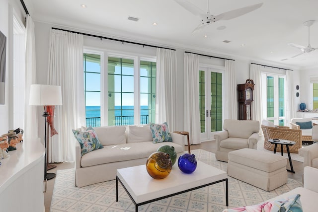 living room featuring ceiling fan, a healthy amount of sunlight, crown molding, and a water view