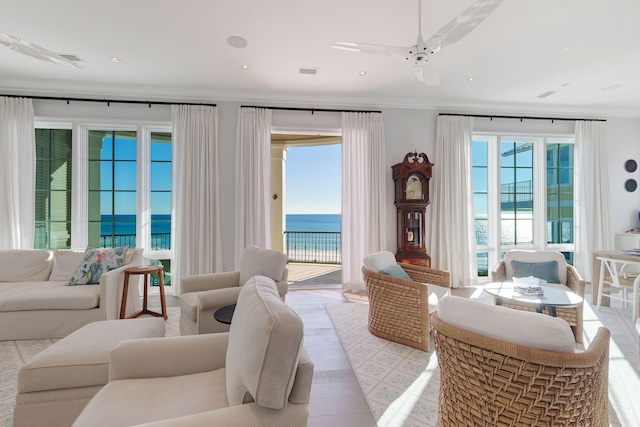 interior space featuring plenty of natural light, ceiling fan, ornamental molding, and a water view