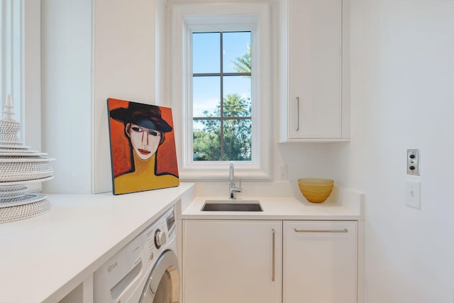 washroom with sink, washer / clothes dryer, and cabinets