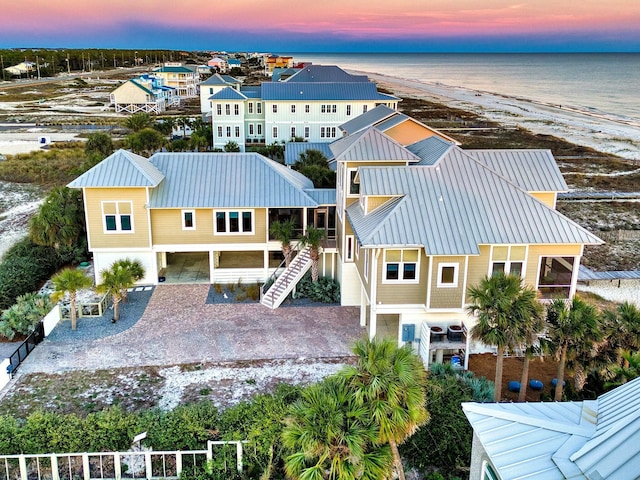 aerial view at dusk with a water view and a beach view