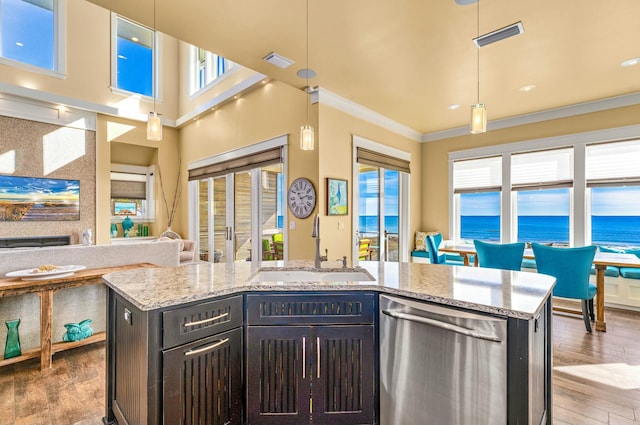 kitchen with stainless steel dishwasher, a water view, sink, and an island with sink