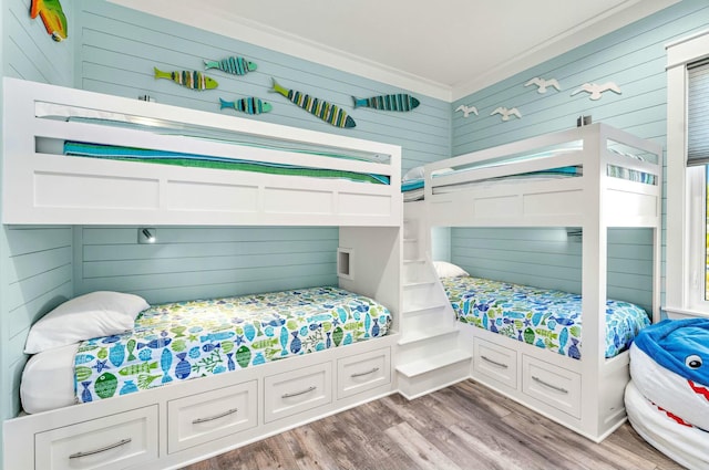 bedroom with hardwood / wood-style floors, ornamental molding, and wood walls