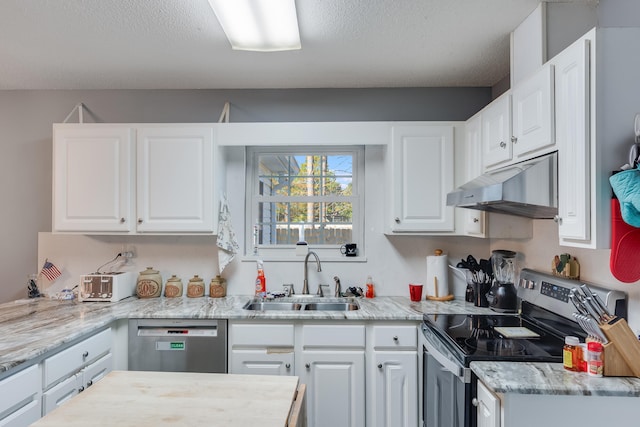 kitchen with stainless steel appliances, a textured ceiling, light stone counters, white cabinets, and sink