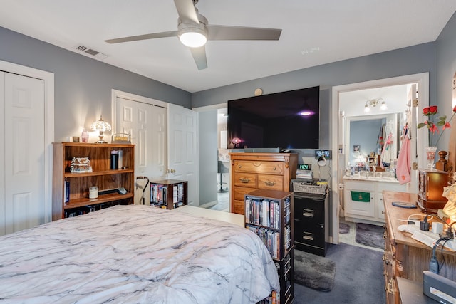 carpeted bedroom featuring ceiling fan, ensuite bathroom, and multiple closets