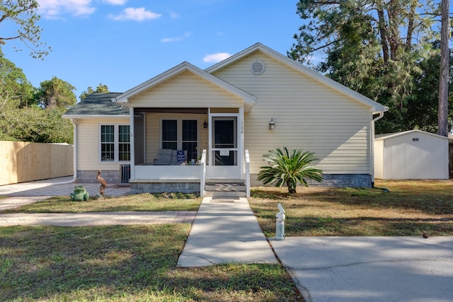 bungalow-style home featuring a front yard, a sunroom, and a storage shed